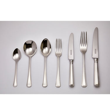 Set of silver cutlery including spoons, forks, and knives on a light gray background