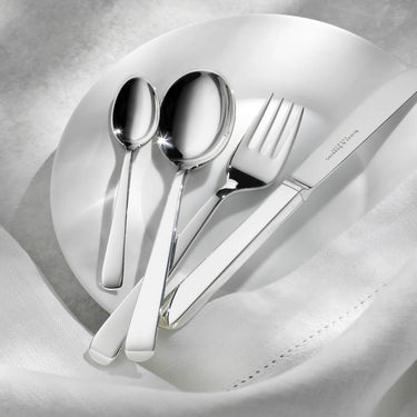 Silver cutlery set on a white napkin with a blurred background
