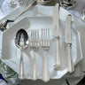 Silver cutlery set on a white plate with a decorative background