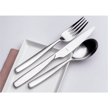 Stainless steel cutlery set on a white surface with a pink napkin.